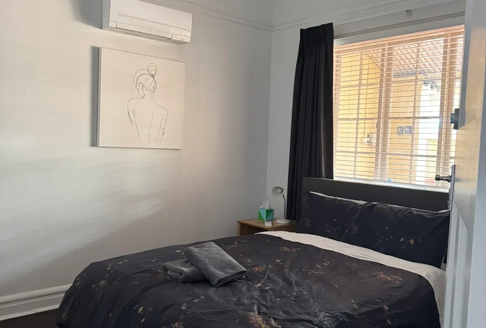 image-5 A bedroom with a bed, nightstand and window.