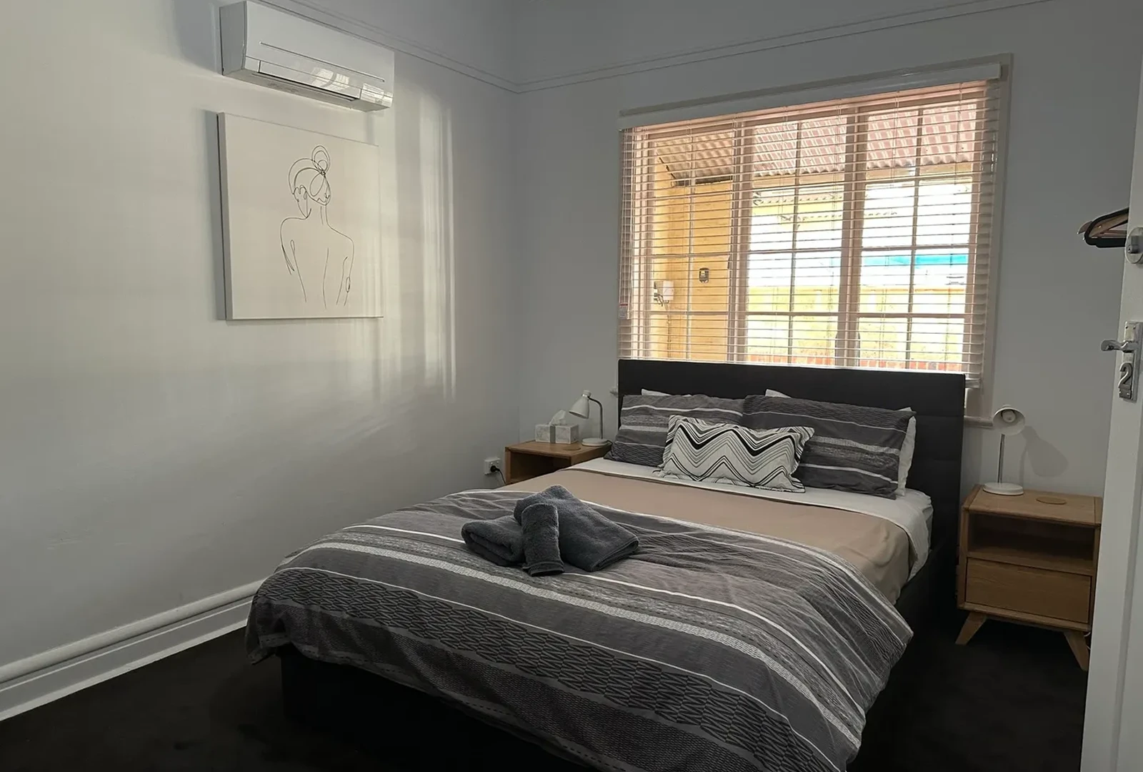image A bedroom with a bed, nightstand and window.